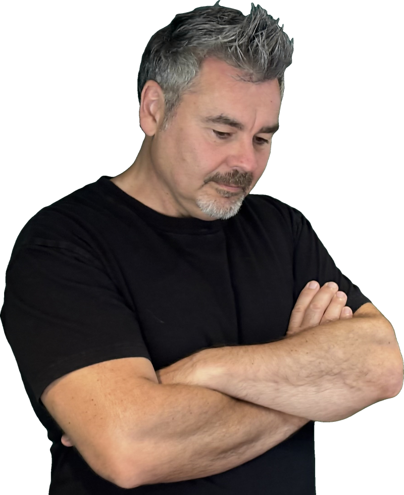 Tristan Alexander in a black T-shirt, arms crossed, looking down thoughtfully