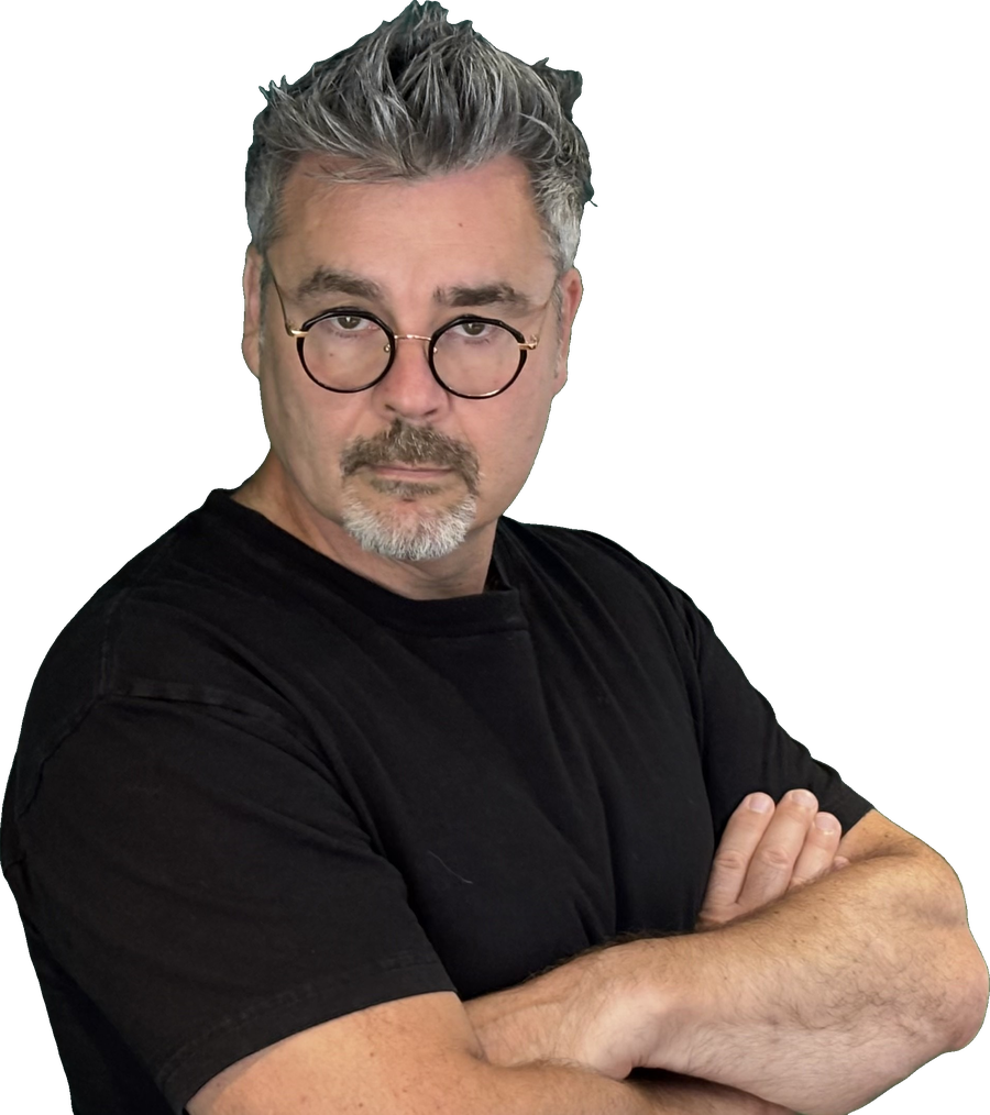 Tristan Alexander in a black T-shirt and round glasses, arms crossed, looking into the camera